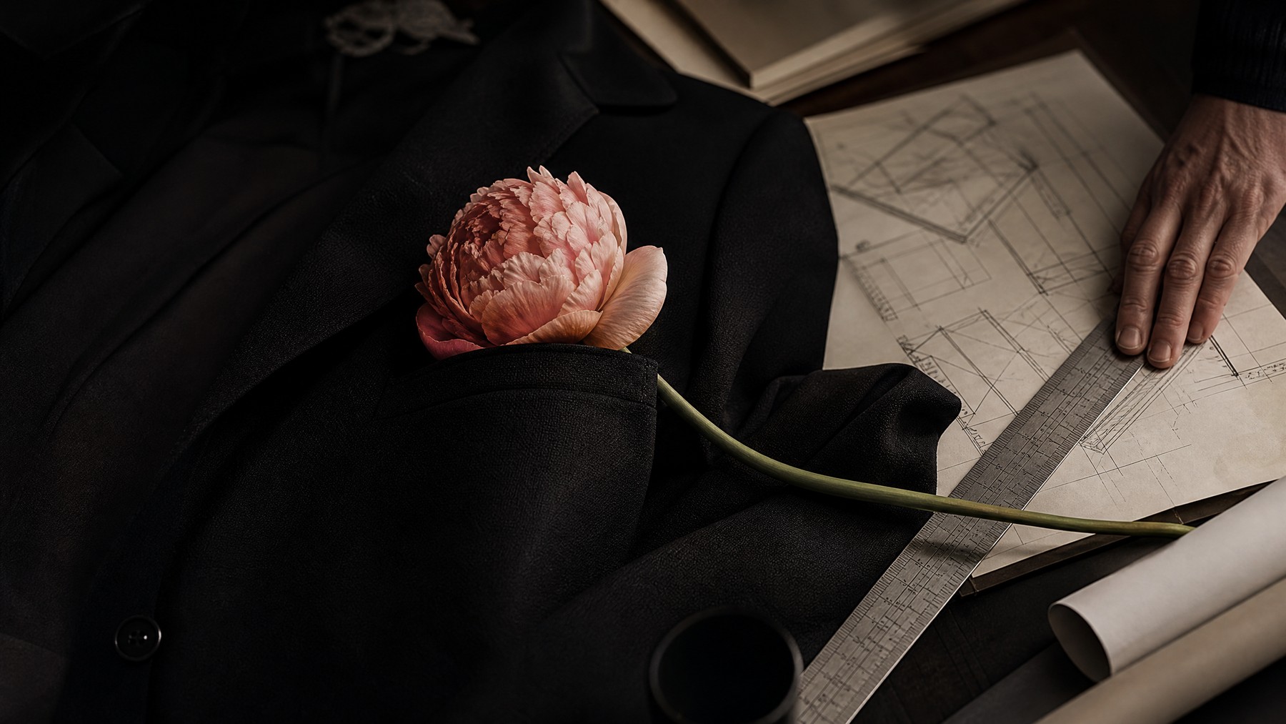 A tailored figure holds a single protea flower over architectural plans, joining human warmth with commercial discipline.