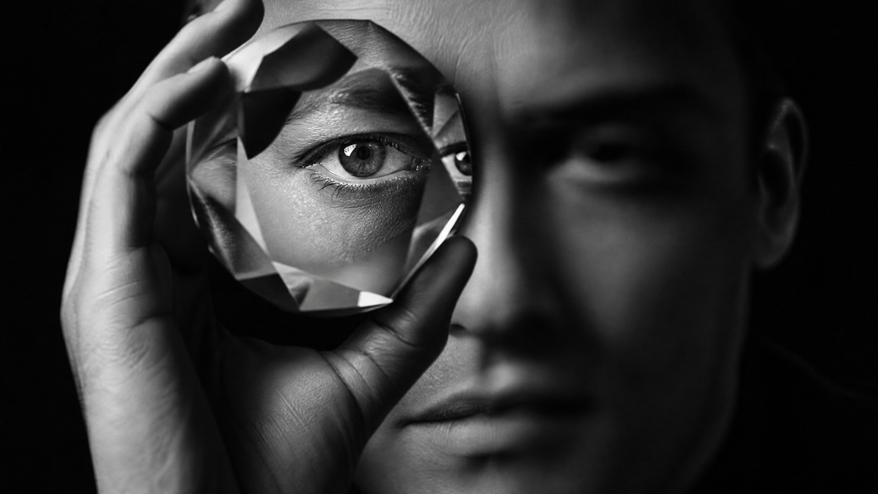 A faceted circular lens brings one eye into precise focus while the surrounding portrait remains soft.